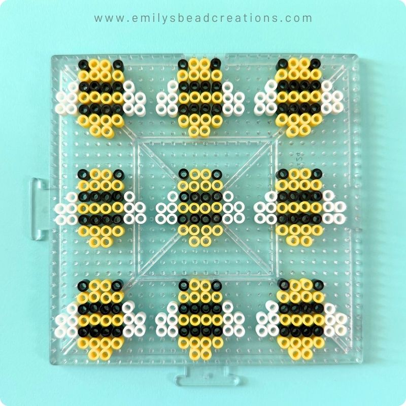 A photo of a large Perler pegboard with yellow, black, and white beads arranged to look like 9 bees.