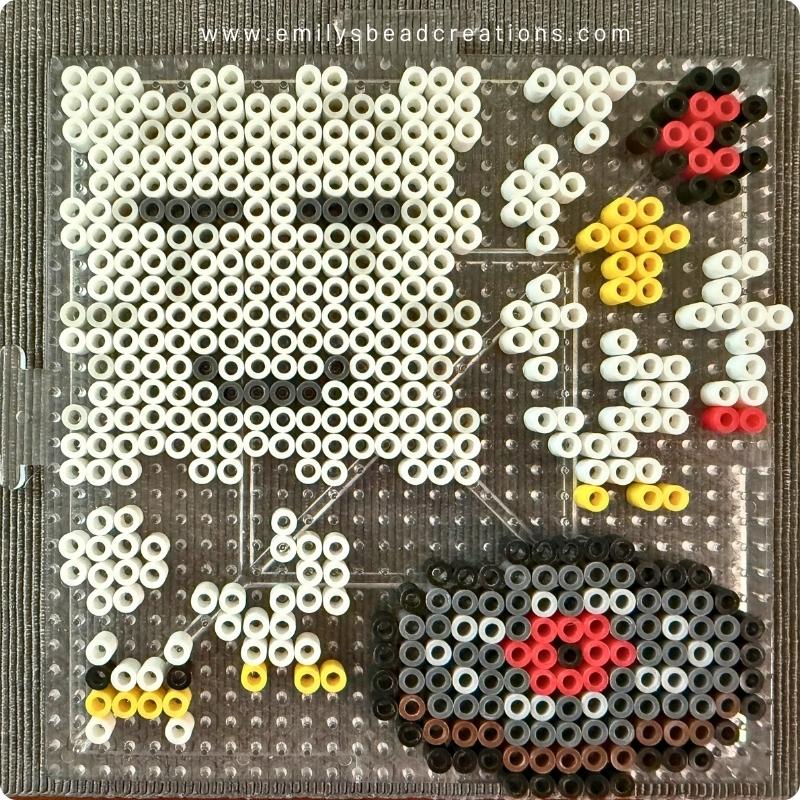 A photo of a large perler pegboard with several bead projects on it, including the happy ghast's face.